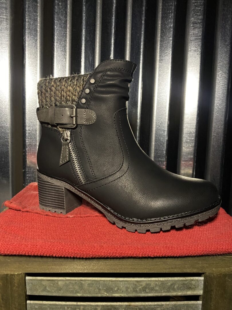 A black boot sitting on top of a red blanket.
