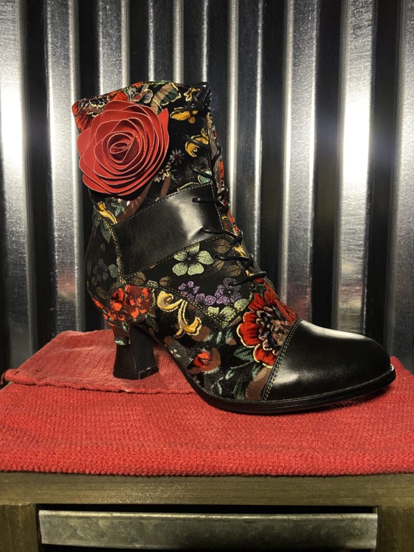 A black and red floral print boot sitting on top of a table.