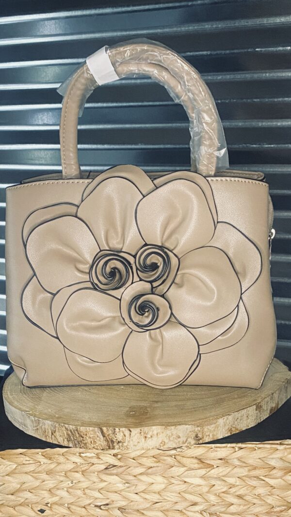 A purse that is made of leather with a flower on it.